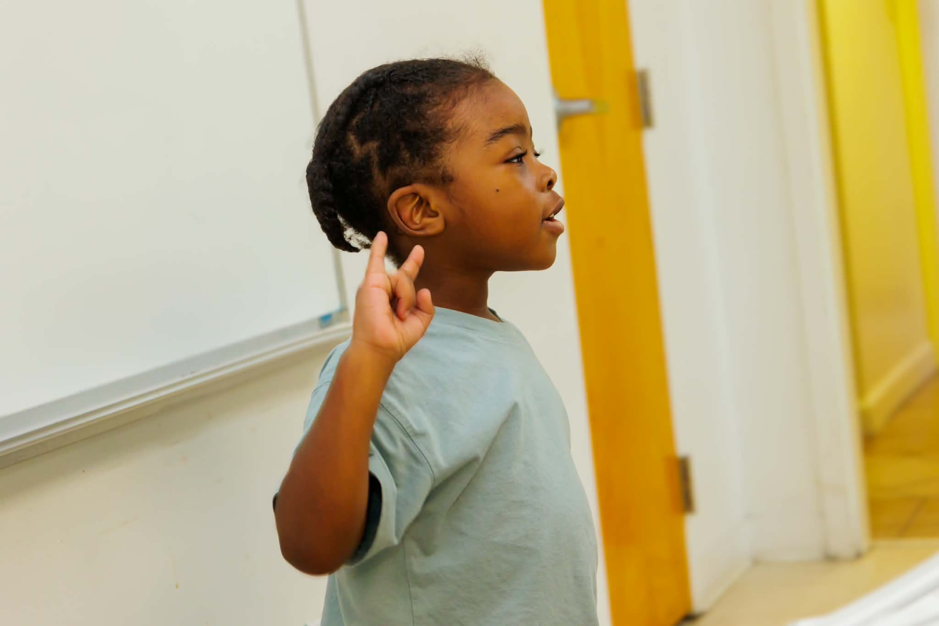 Student raising a hand and answering aloud during a lesson